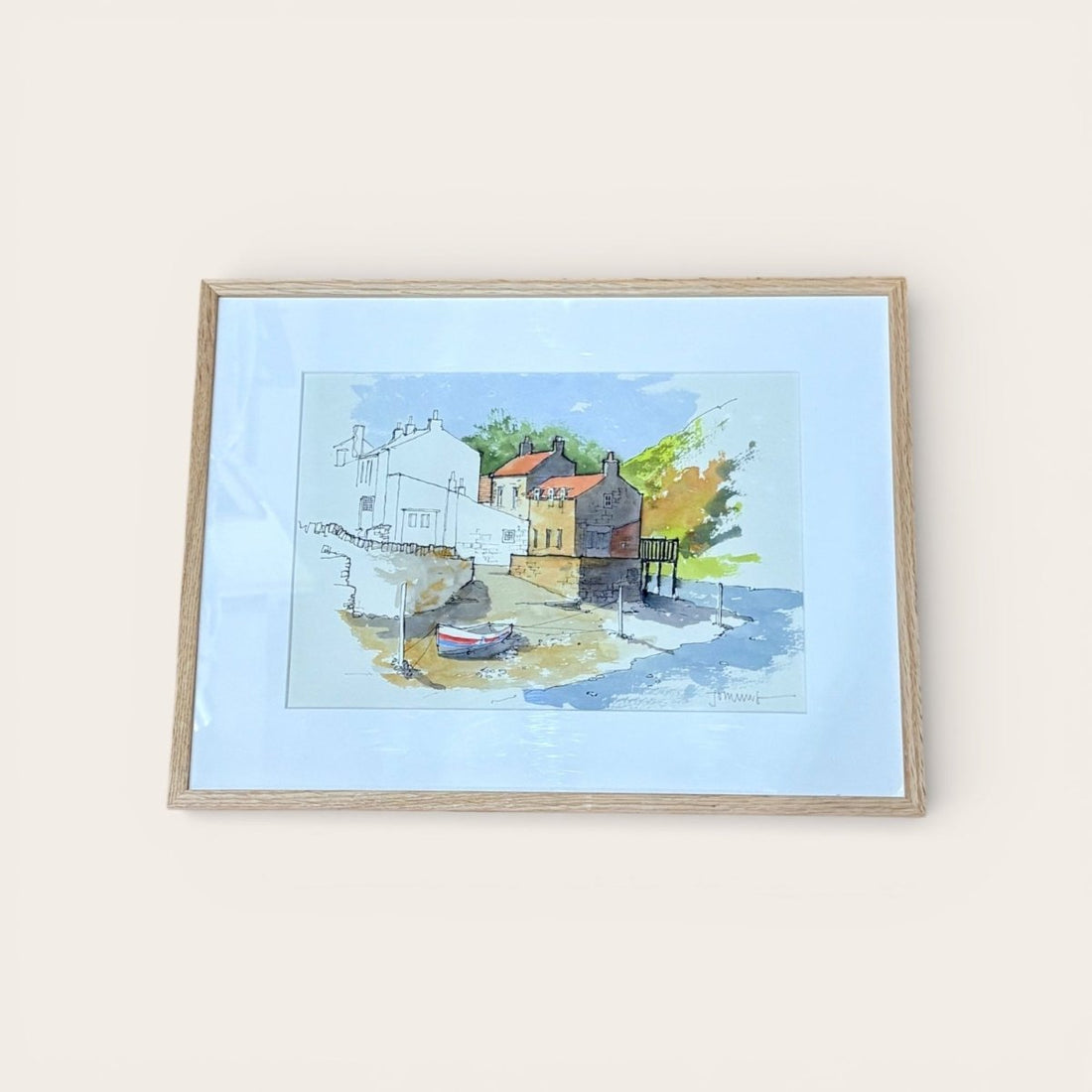 Framed artwork of a coastal scene with houses and boats on a light blue background.