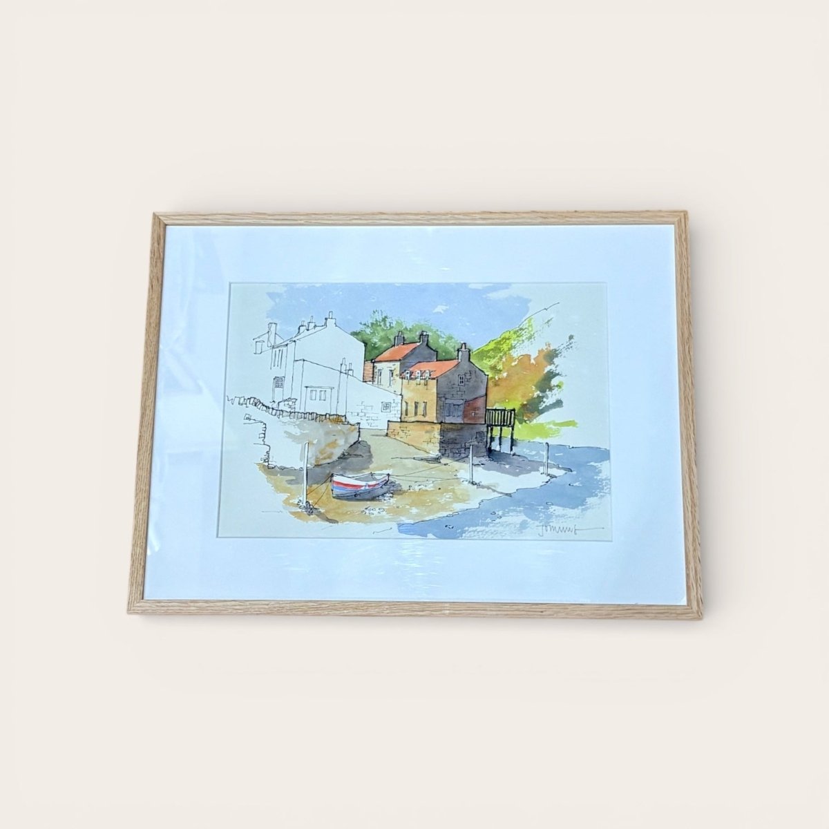 Framed artwork of a coastal scene with houses and boats on a light blue background.