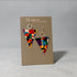 Triangle dangle earrings with a colorful geometric abstract pattern, displayed on a brown Nancy Jones brand card against a neutral gray background.
