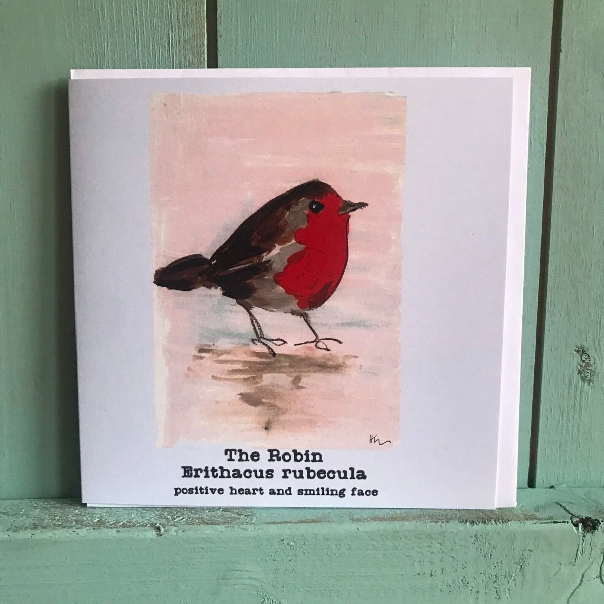 Card with a robin illustration and text on a green wooden surface