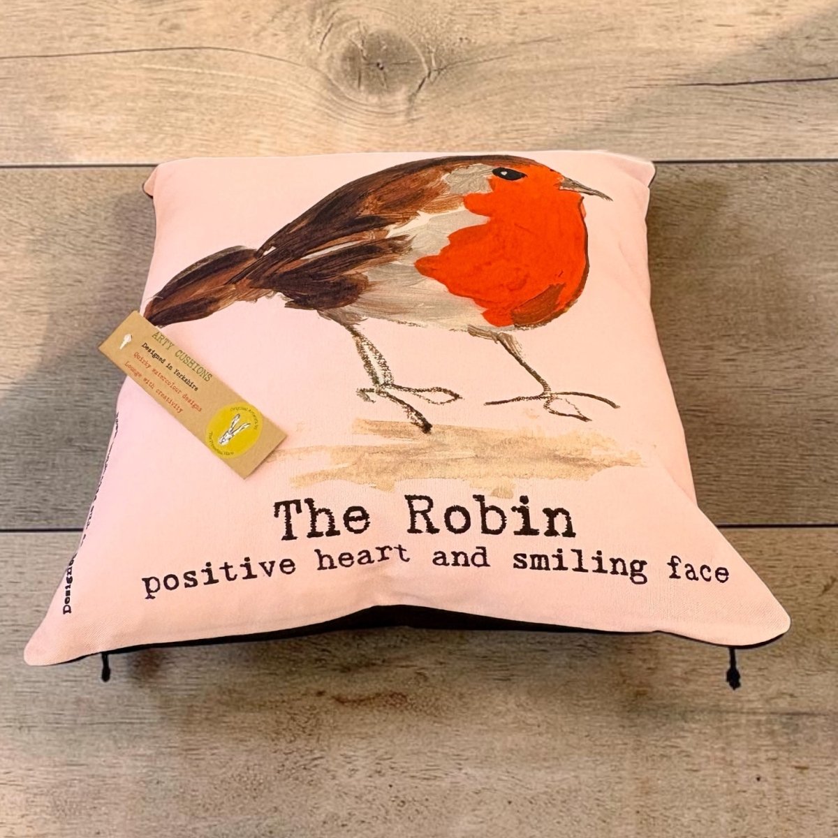 A square pink throw pillow featuring a painted robin bird and the text &