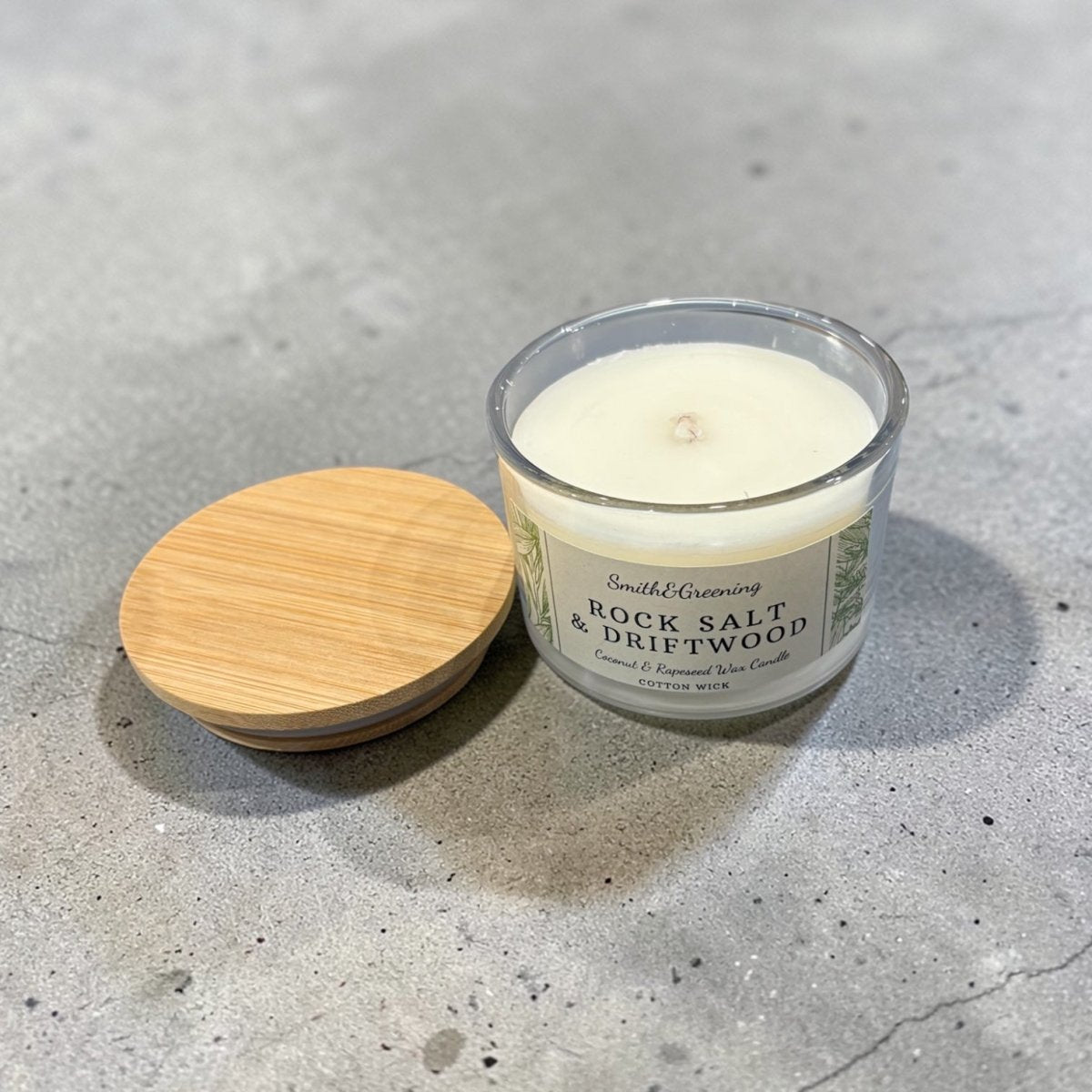 Candle with wooden lid on a concrete surface