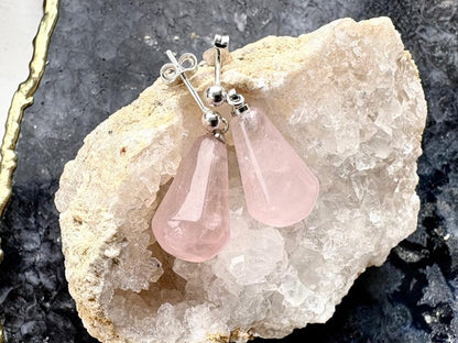 Pink teardrop earrings on a stone background