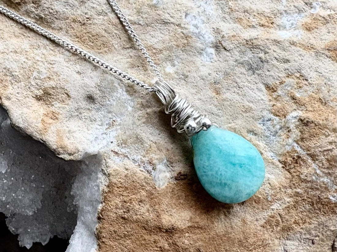 Turquoise teardrop pendant necklace on a stone surface