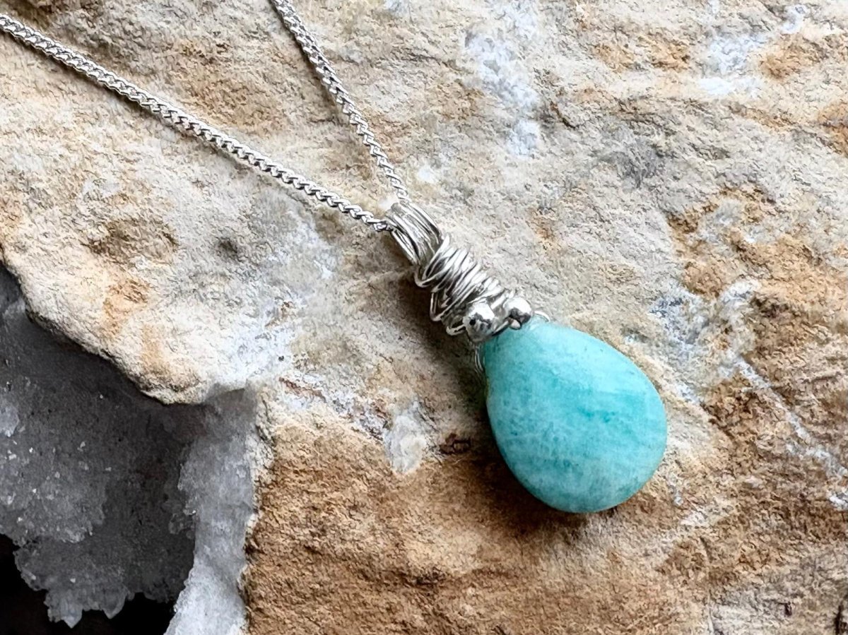 Turquoise teardrop pendant necklace on a stone surface