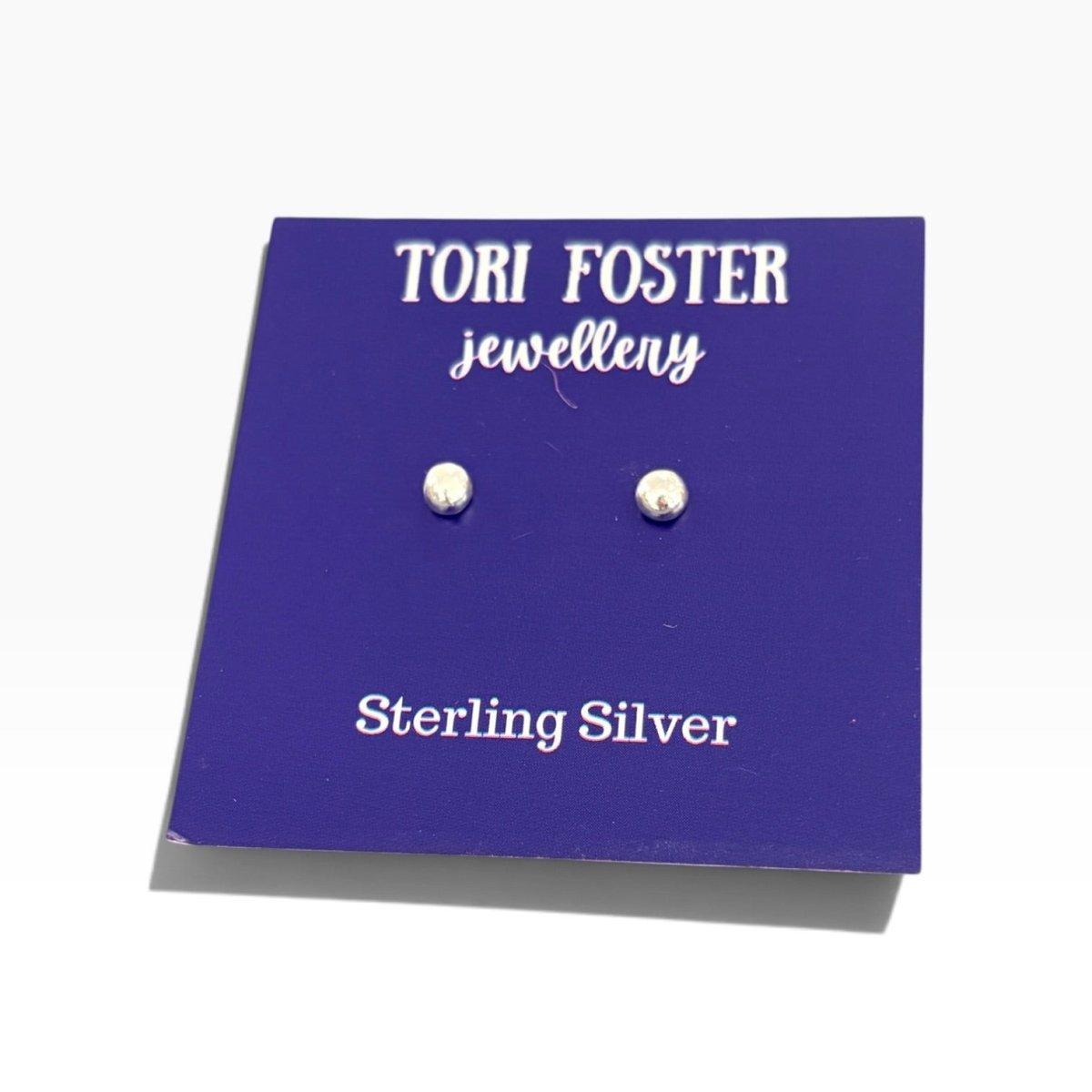 A pair of sterling silver stud earrings displayed on a purple backing card that reads &