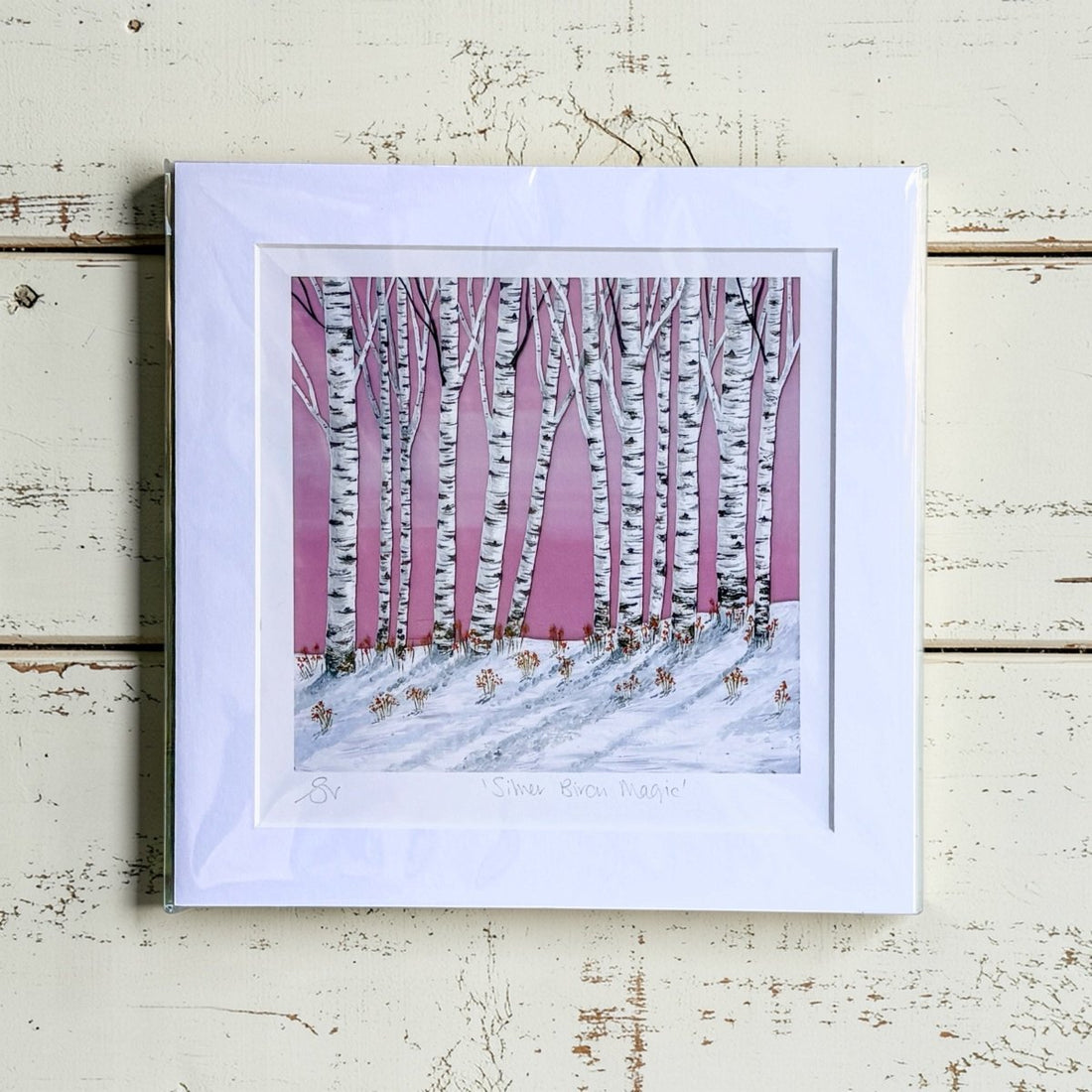 Framed artwork of a snowy landscape with birch trees on a pink background