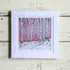 Framed artwork of a snowy landscape with birch trees on a pink background