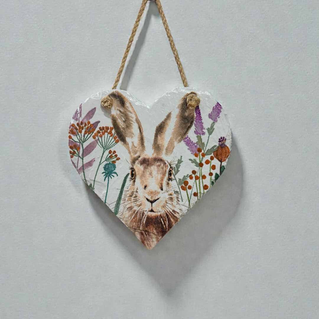 Heart-shaped wooden plaque with a hare illustration and floral elements on a light gray background.