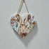 Heart-shaped wooden plaque with a hare illustration and floral elements on a light gray background.