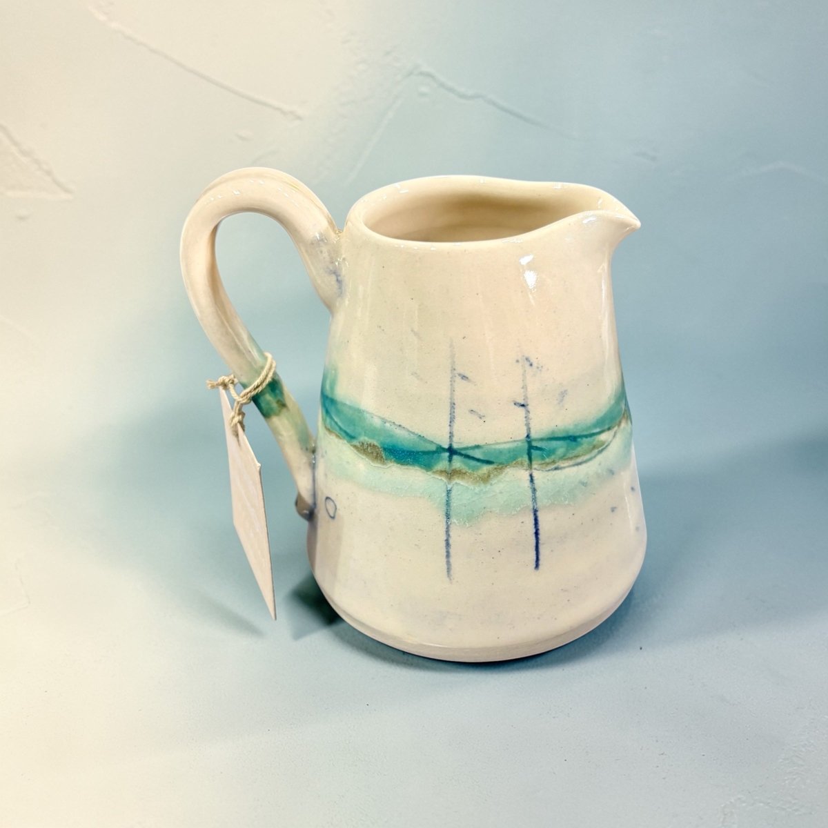 Ceramic pitcher with artistic design on a light blue background
