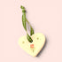 A glossy cream-colored ceramic heart ornament with a green and white polka-dot ribbon loop, decorated with a small red tulip and gold stars on a pale pink background.