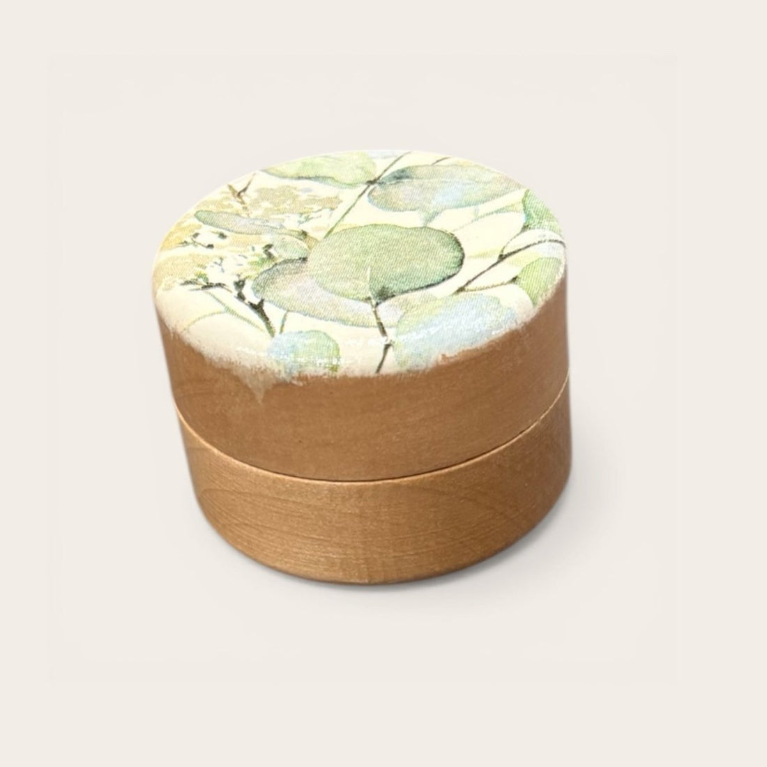 Round brown box with a floral lid on a white background