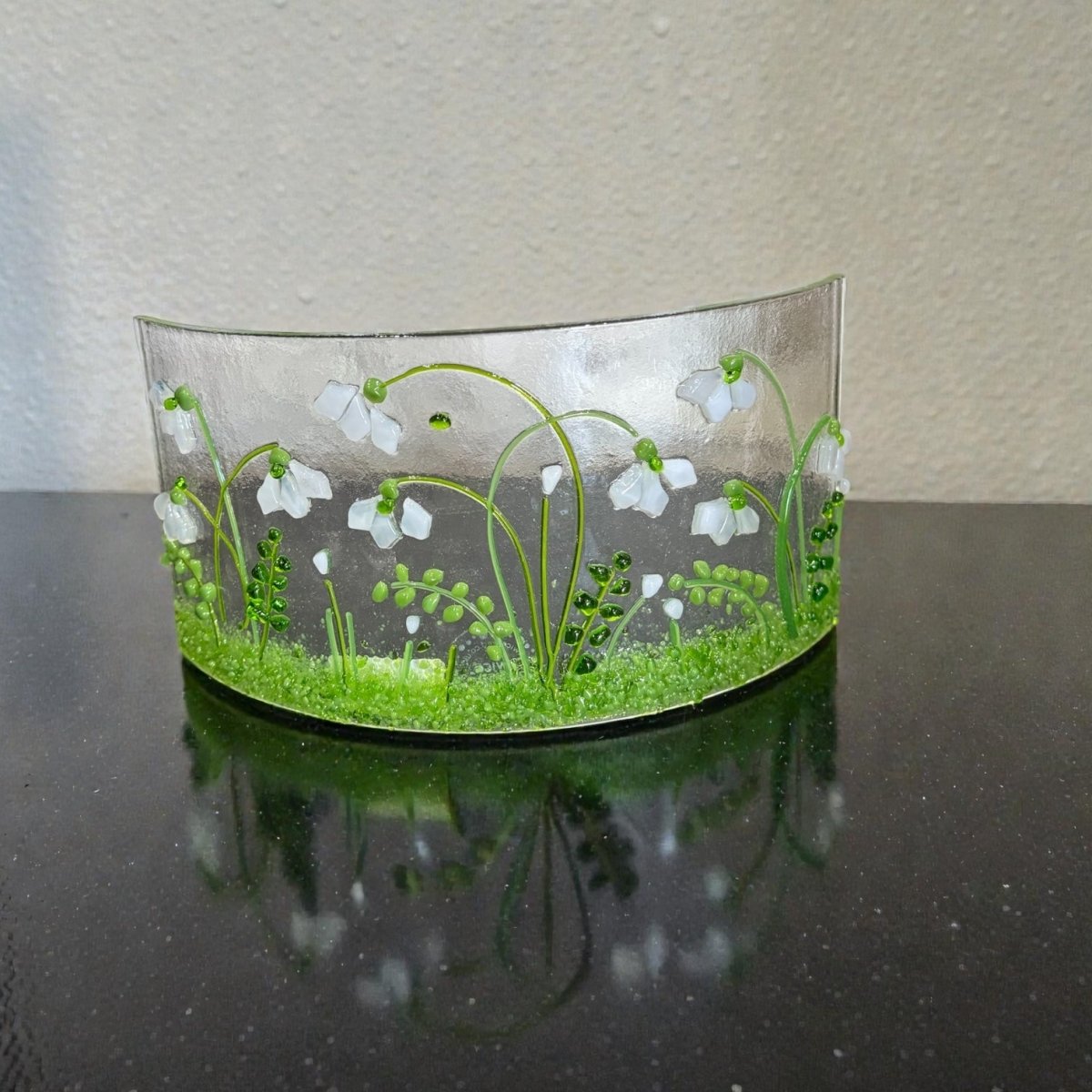 Decorative glass piece with floral design on a reflective surface