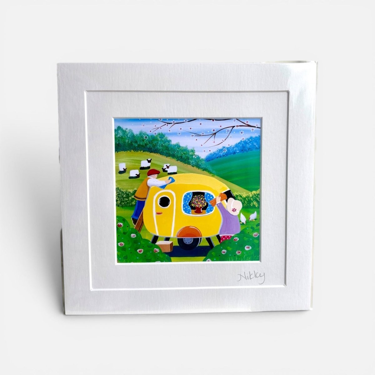 Framed artwork of a yellow caravan with people and animals in a scenic setting.