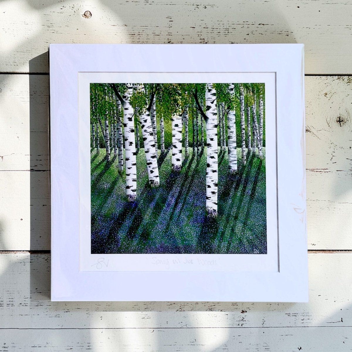 Framed artwork of a birch tree forest on a wooden surface