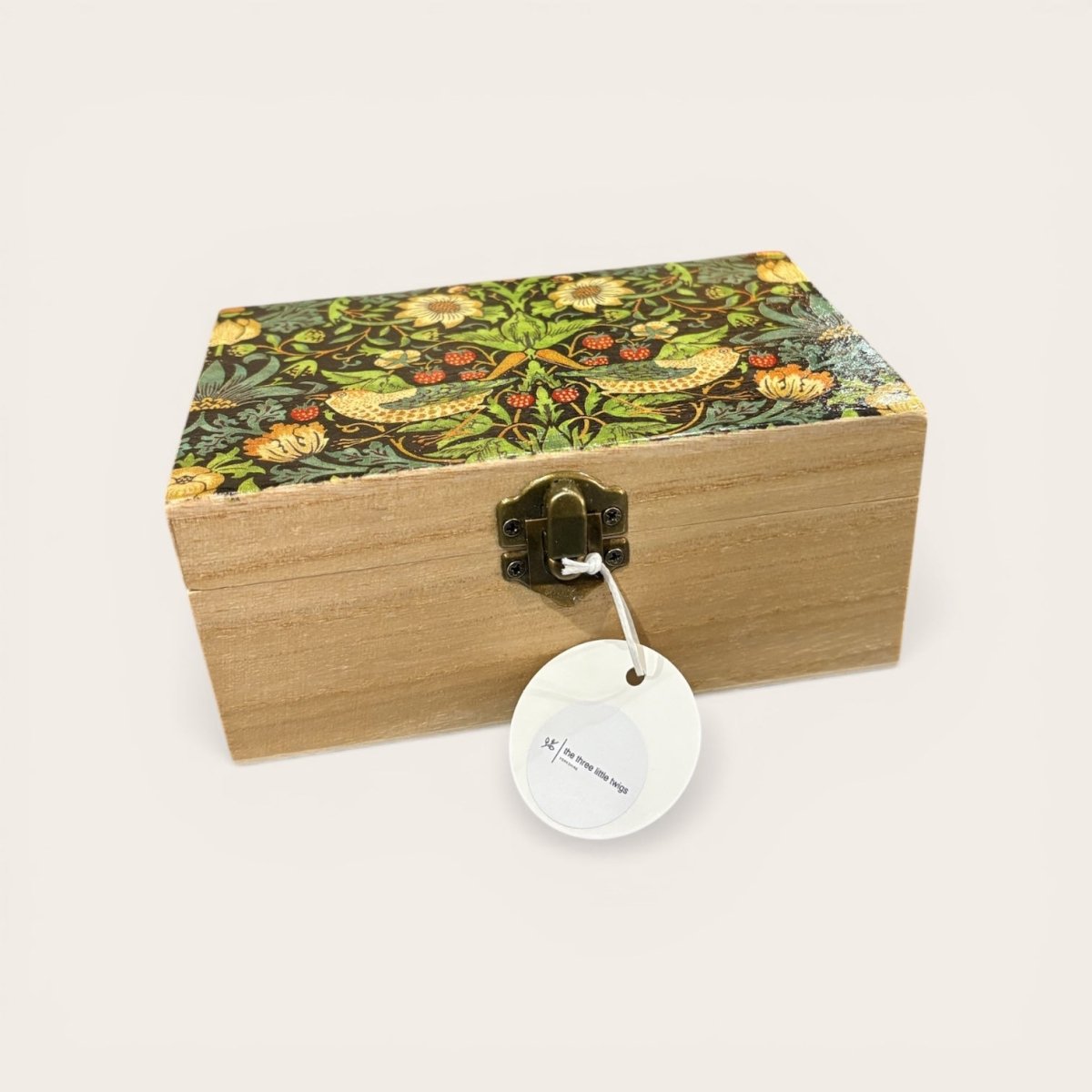 Wooden box with floral patterned lid and decorative tag on a white background