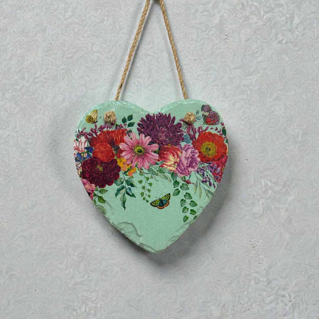Heart-shaped decorative item with floral design hanging on a textured wall.