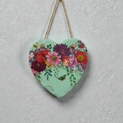 Heart-shaped decorative item with floral design hanging on a textured wall.