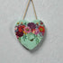 Heart-shaped decorative item with floral design hanging on a textured wall.