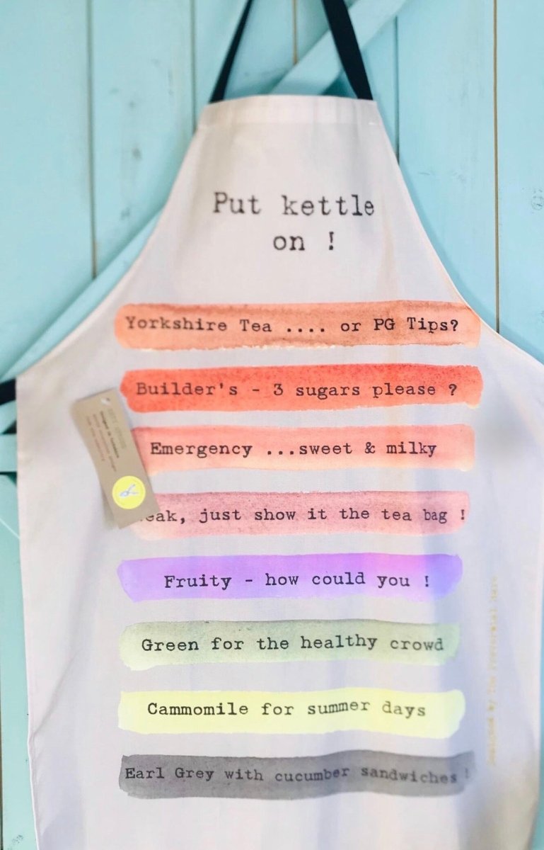 A white kitchen apron with black straps, featuring humorous printed text in black typewriter font over pastel watercolor stripes in orange, pink, green, purple, yellow, and gray. The text reads &