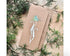 Kraft paper card with floral design on a bed of greenery