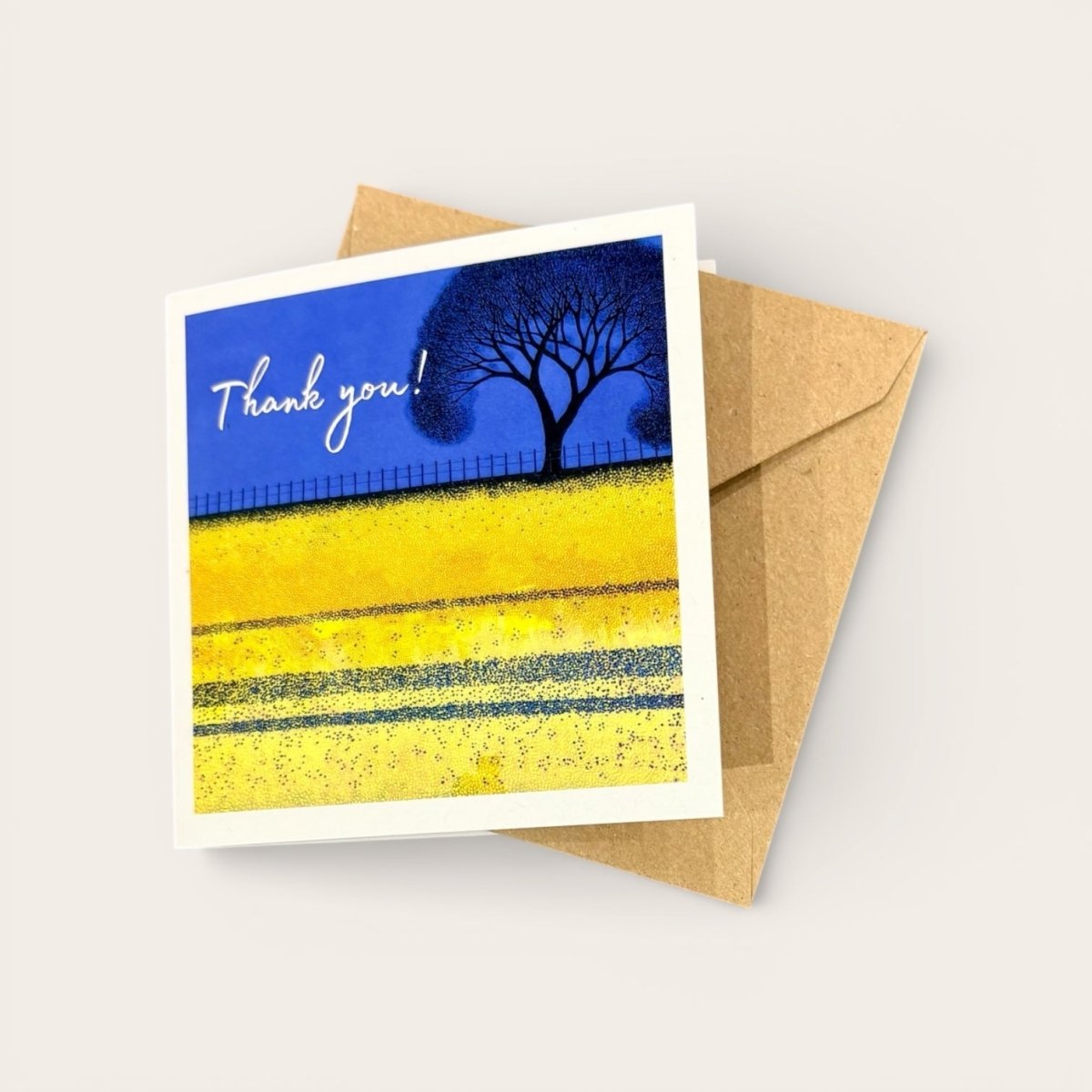 Greeting card with a blue sky, yellow field, and tree, featuring the text &