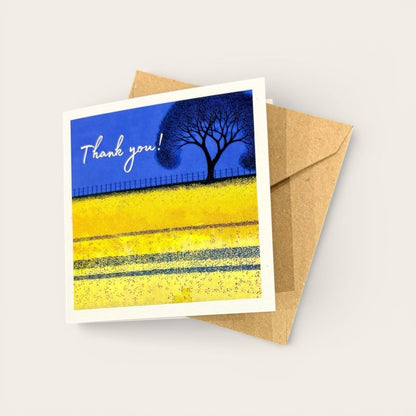 Greeting card with a blue sky, yellow field, and tree, featuring the text &