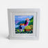Framed artwork of a woman with a dog and cat sitting in a garden with mountains in the background.