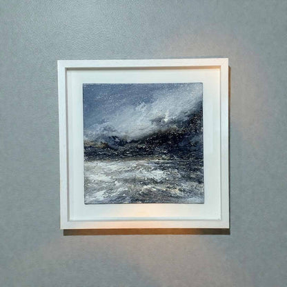 Framed artwork of a stormy sea on a gray wall