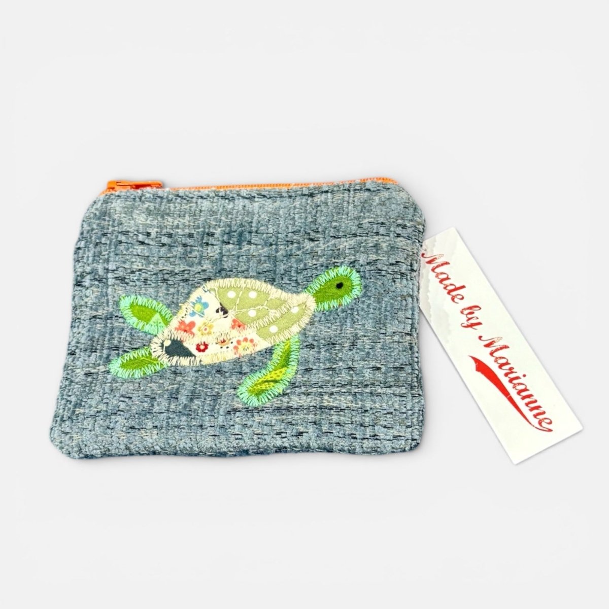 Textured pouch with a turtle design and a tag reading &