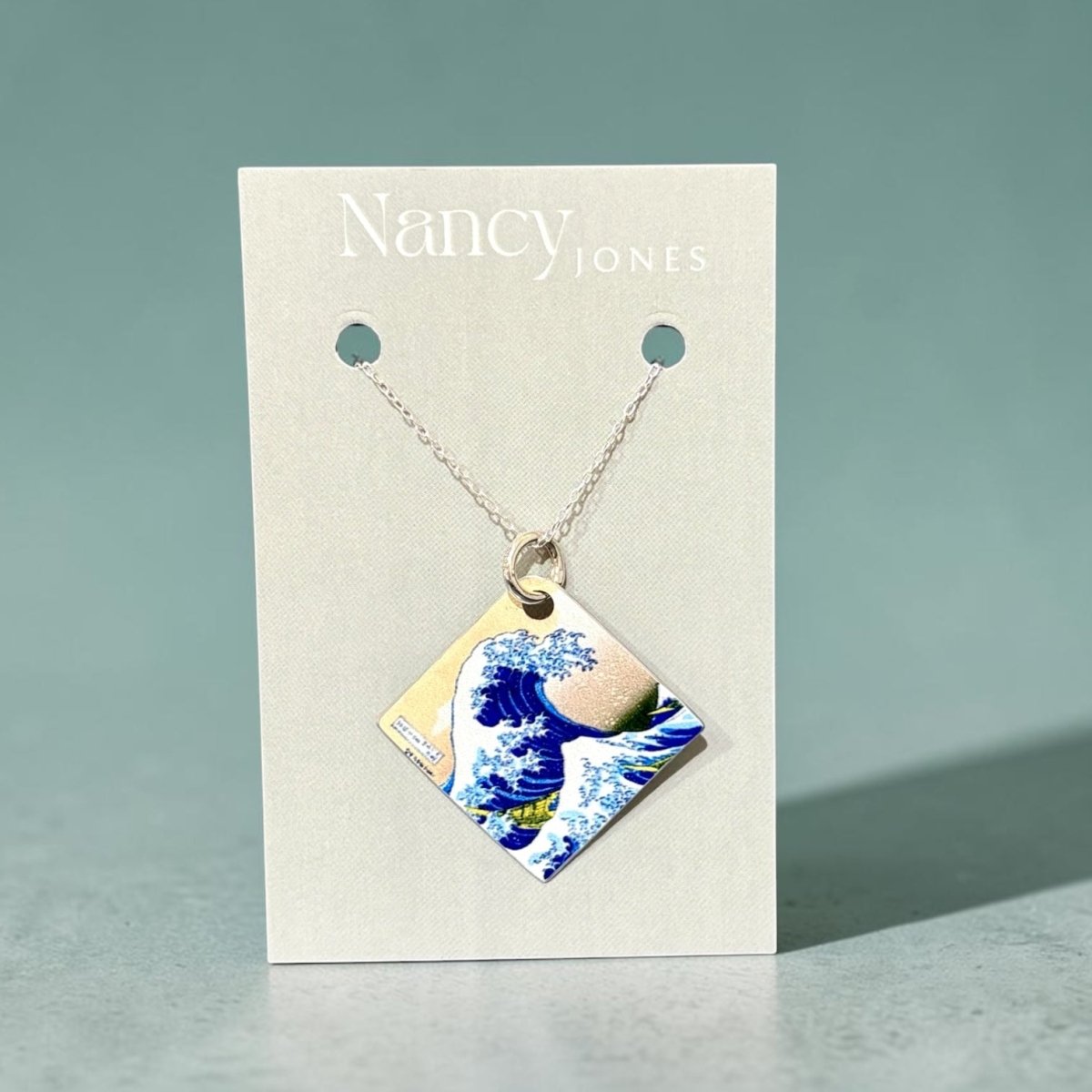 Necklace with a wave design pendant on a Nancy Jones card against a light gray background