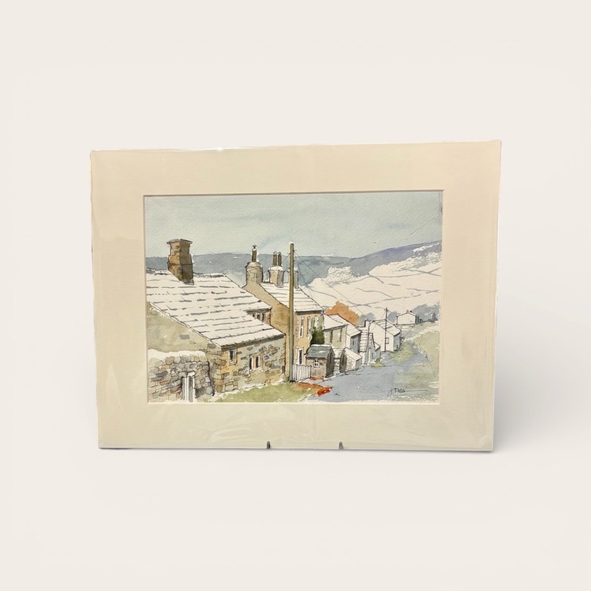 Framed artwork of a snowy village scene with houses and chimneys.
