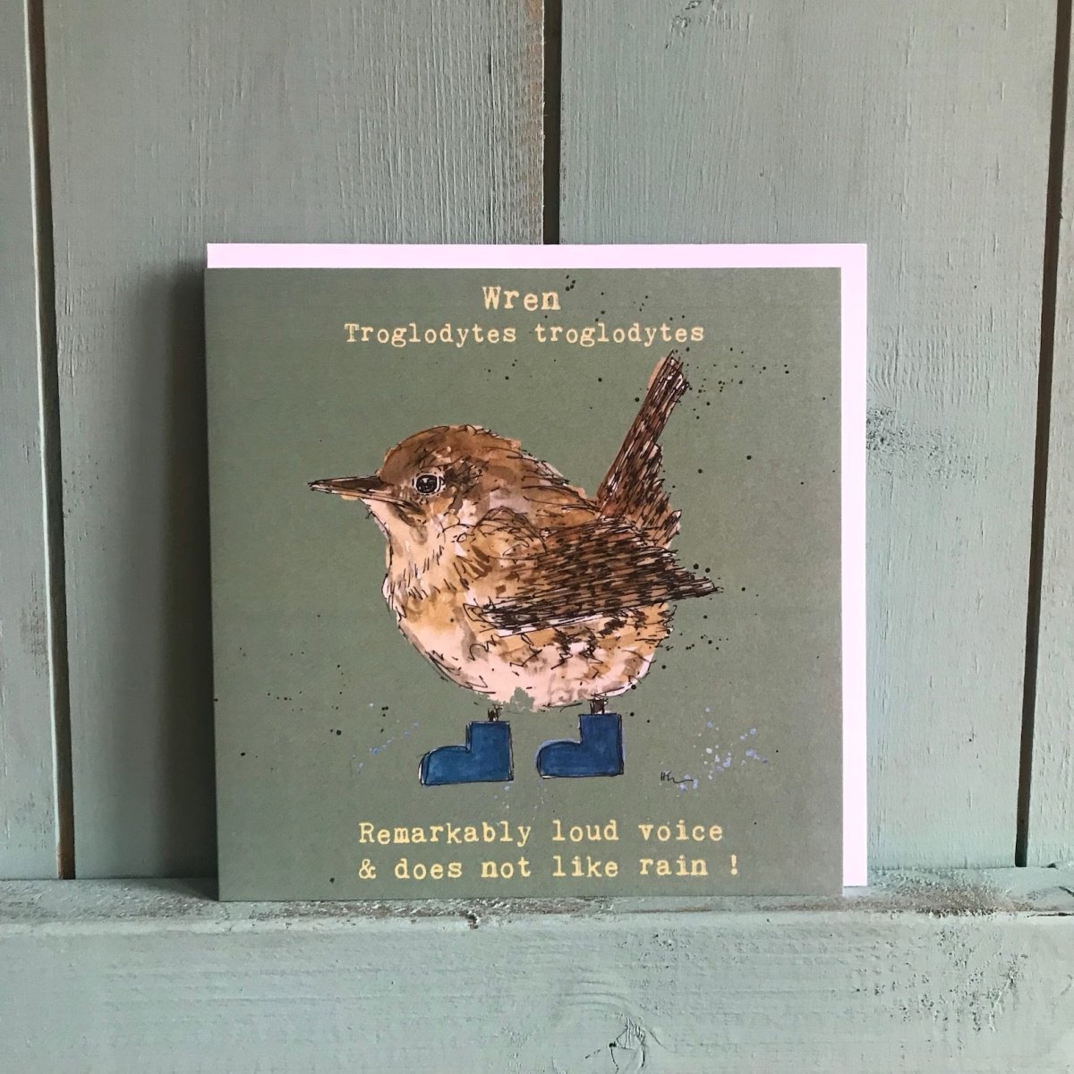 Card with a wren illustration and text on a wooden surface