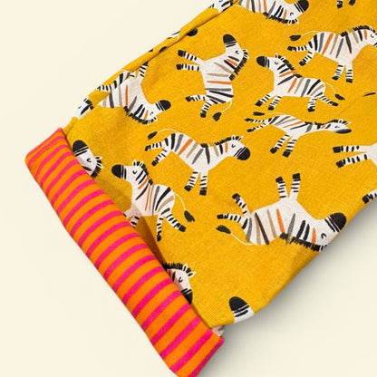 Fabric with zebra pattern and pink/orange striped edge on a beige background