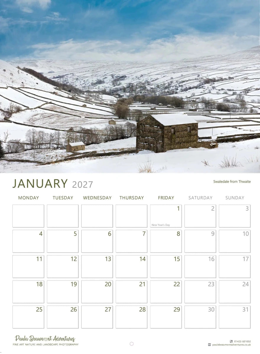 A January 2027 wall calendar page featuring a snowy mountain landscape photograph with a small stone building, above a grid of dates and the title January 2027.