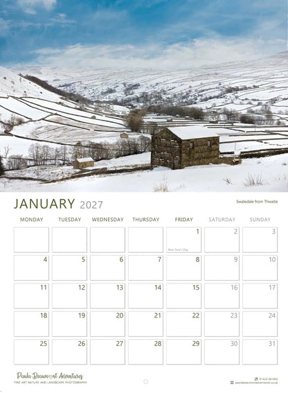 A January 2027 wall calendar page featuring a snowy mountain landscape photograph with a small stone building, above a grid of dates and the title January 2027.